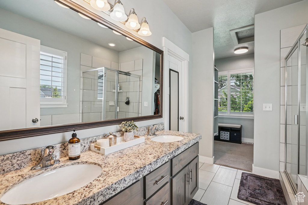 Full bathroom with a shower stall, double vanity, and tile patterned flooring