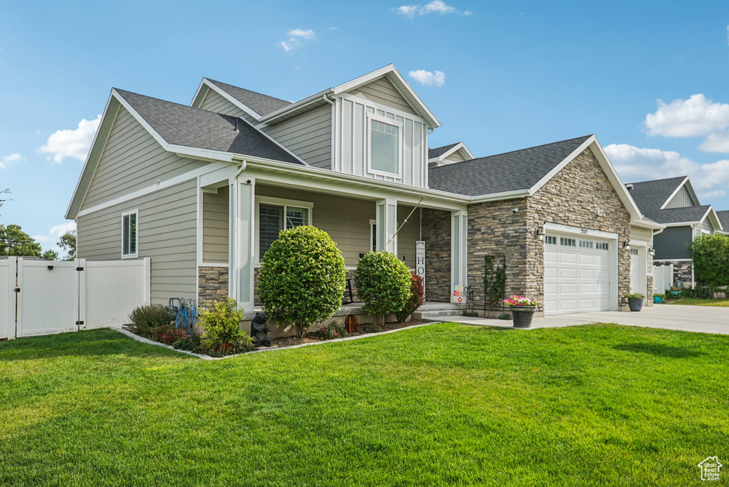 Craftsman-style home featuring a gate, stone siding, a garage, a porch, and driveway