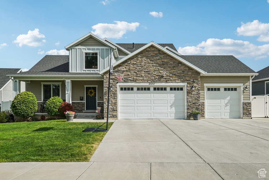 Craftsman house with stone siding, concrete driveway, a garage, a front yard, and a shingled roof
