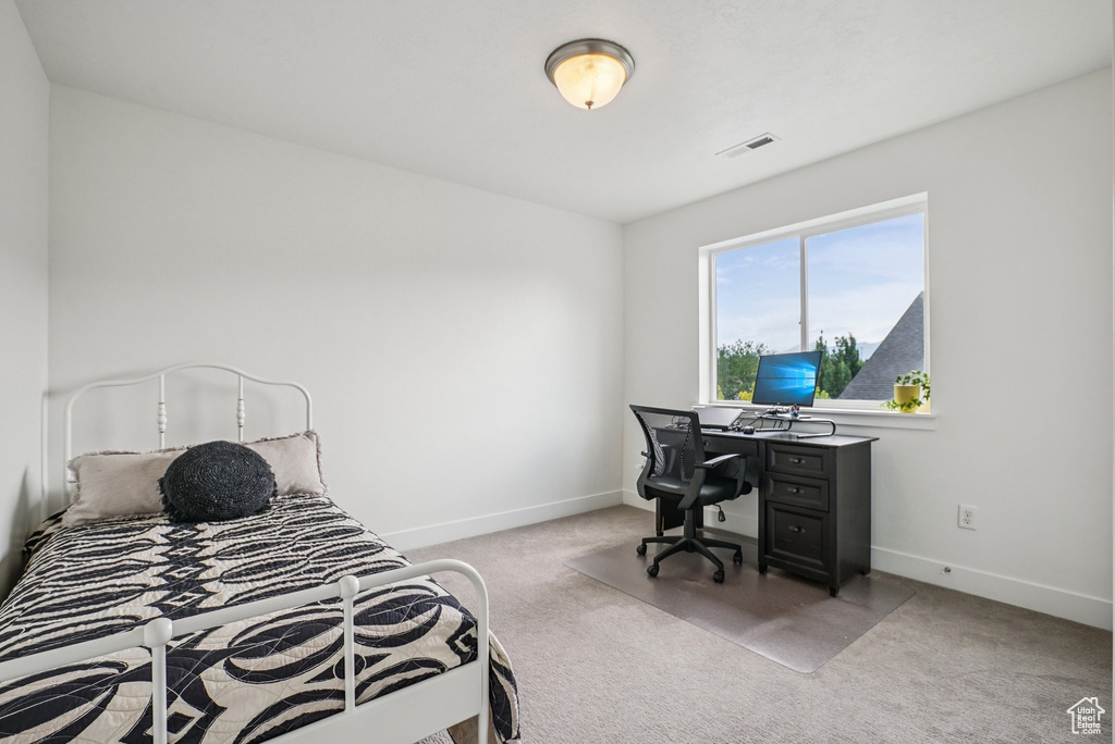 Bedroom featuring light carpet and an office area