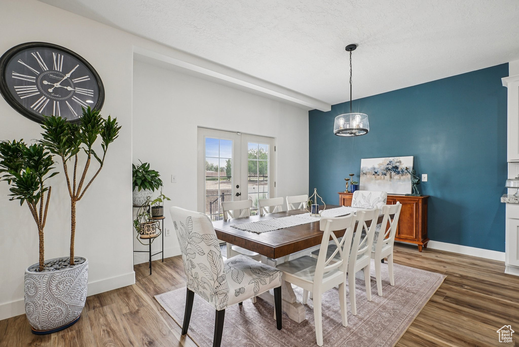 Dining room featuring light wood-type flooring, french doors, and a chandelier