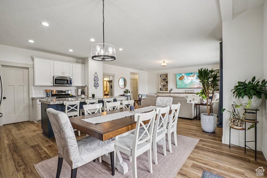 Dining area with light wood-style flooring, recessed lighting, and a chandelier