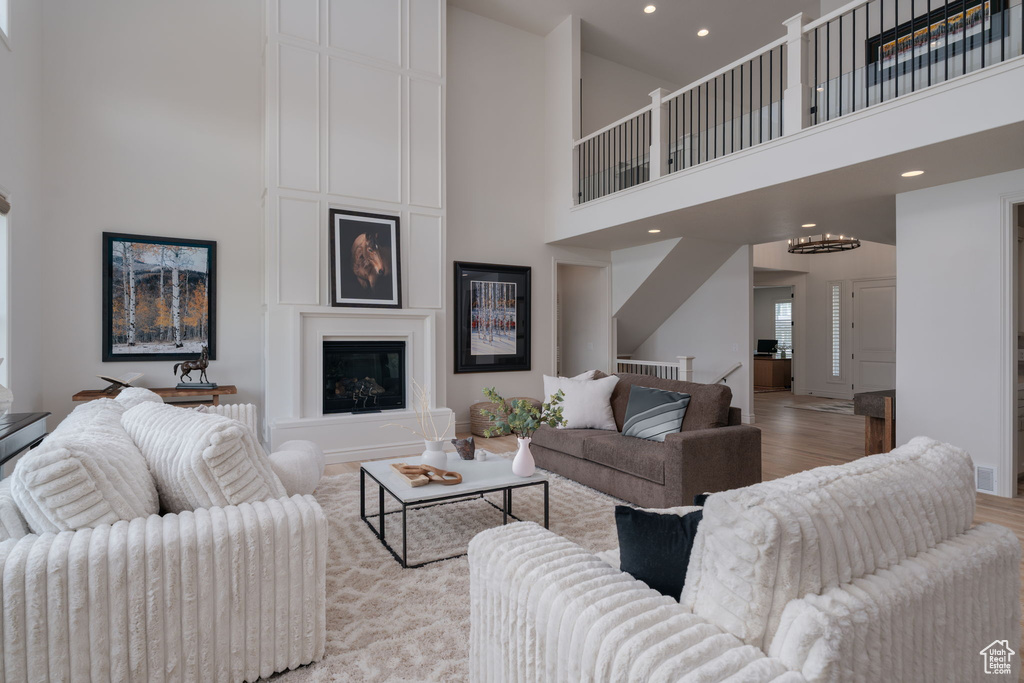 Living room featuring a towering ceiling, light wood-style flooring, and recessed lighting