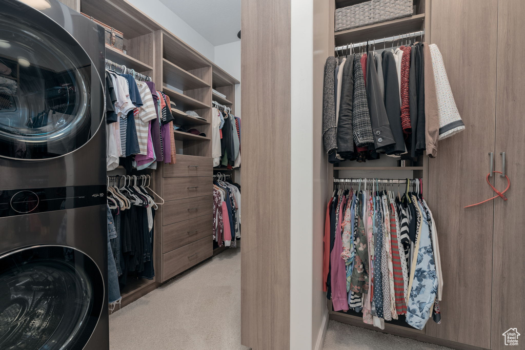 Walk in closet with stacked washer / dryer and carpet floors