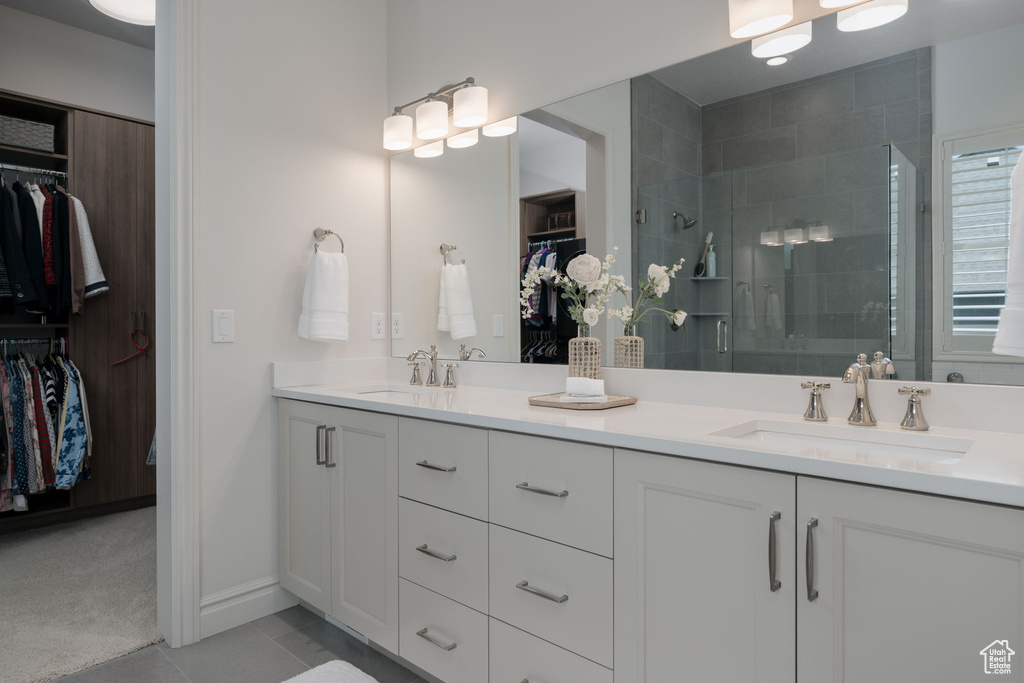 Bathroom featuring a spacious closet, double vanity, a shower stall, and tile patterned flooring