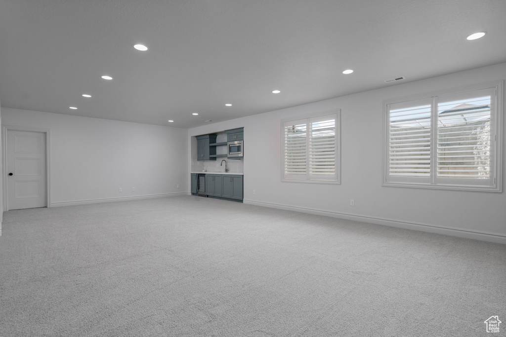 Unfurnished living room with recessed lighting, light colored carpet, and wet bar