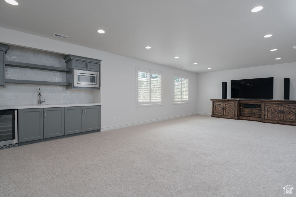 Unfurnished living room featuring wine cooler, wet bar, light colored carpet, and recessed lighting
