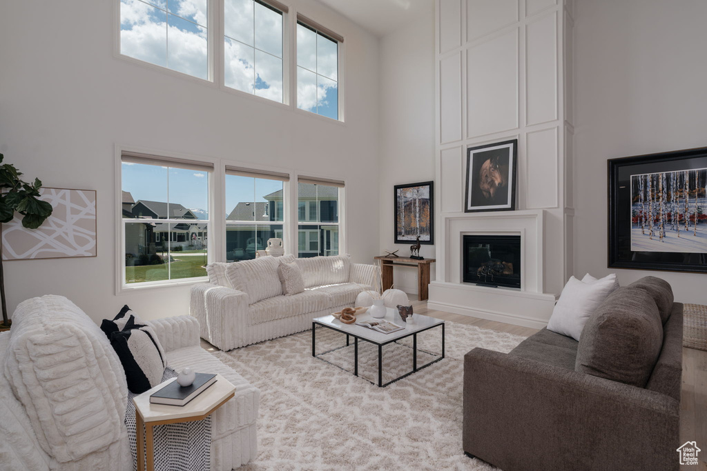 Living area with a high ceiling, wood finished floors, and a fireplace
