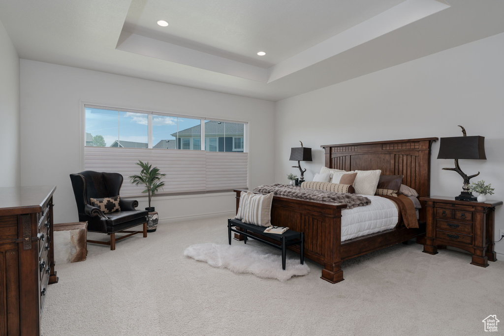 Bedroom with light carpet, recessed lighting, and a raised ceiling