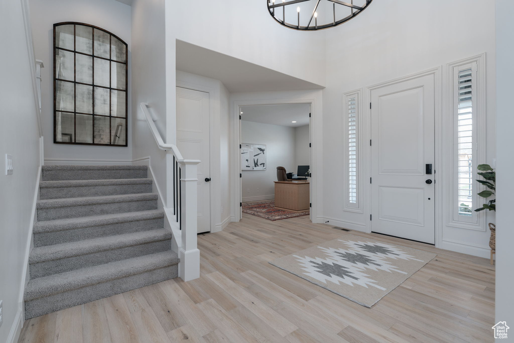 Entryway with light wood-style floors, stairway, a chandelier, and a high ceiling