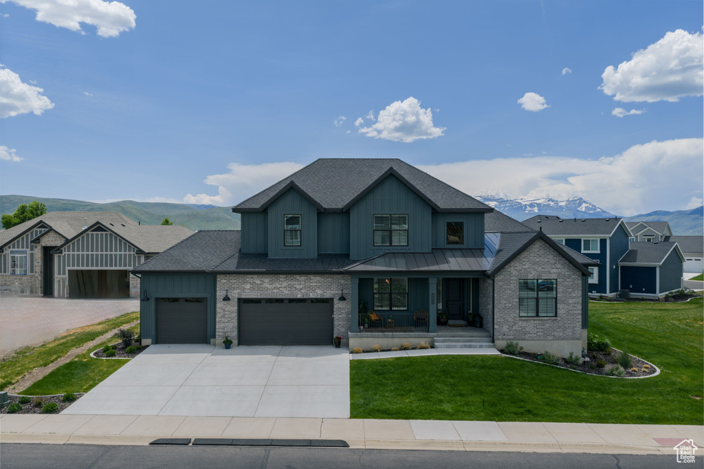 View of front of house featuring a porch, a front yard, board and batten siding, concrete driveway, and a mountain view