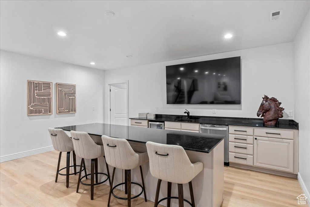 Bar featuring stainless steel dishwasher, light wood-type flooring, and recessed lighting