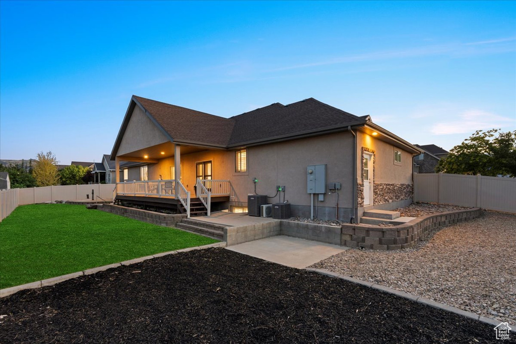 Back of property featuring stucco siding, a fenced backyard, a wooden deck, and a patio area