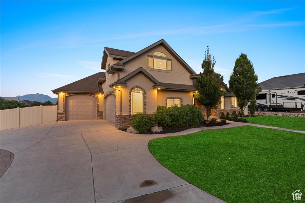 View of front of property featuring driveway, stone siding, a garage, stucco siding, and a mountain view