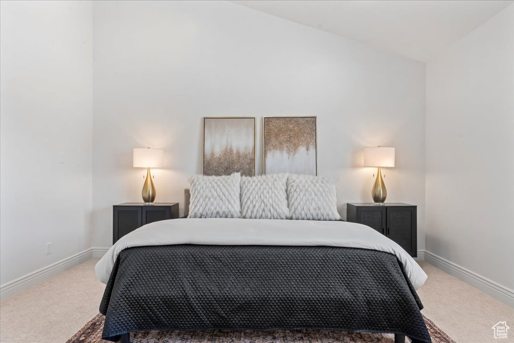 Carpeted bedroom featuring lofted ceiling and baseboards