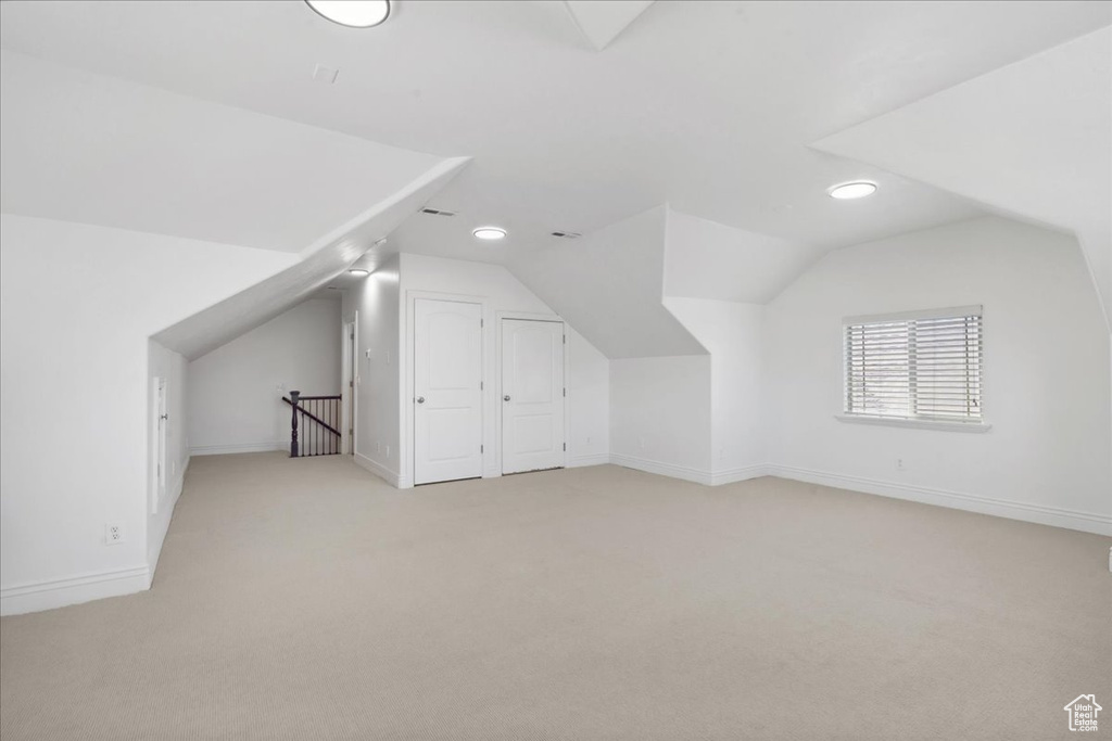 Additional living space featuring lofted ceiling and light colored carpet