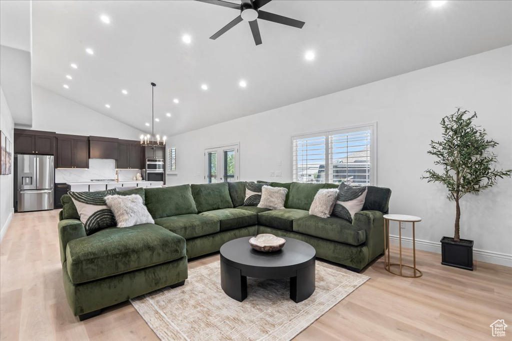 Living area featuring high vaulted ceiling, light wood finished floors, a chandelier, a ceiling fan, and recessed lighting
