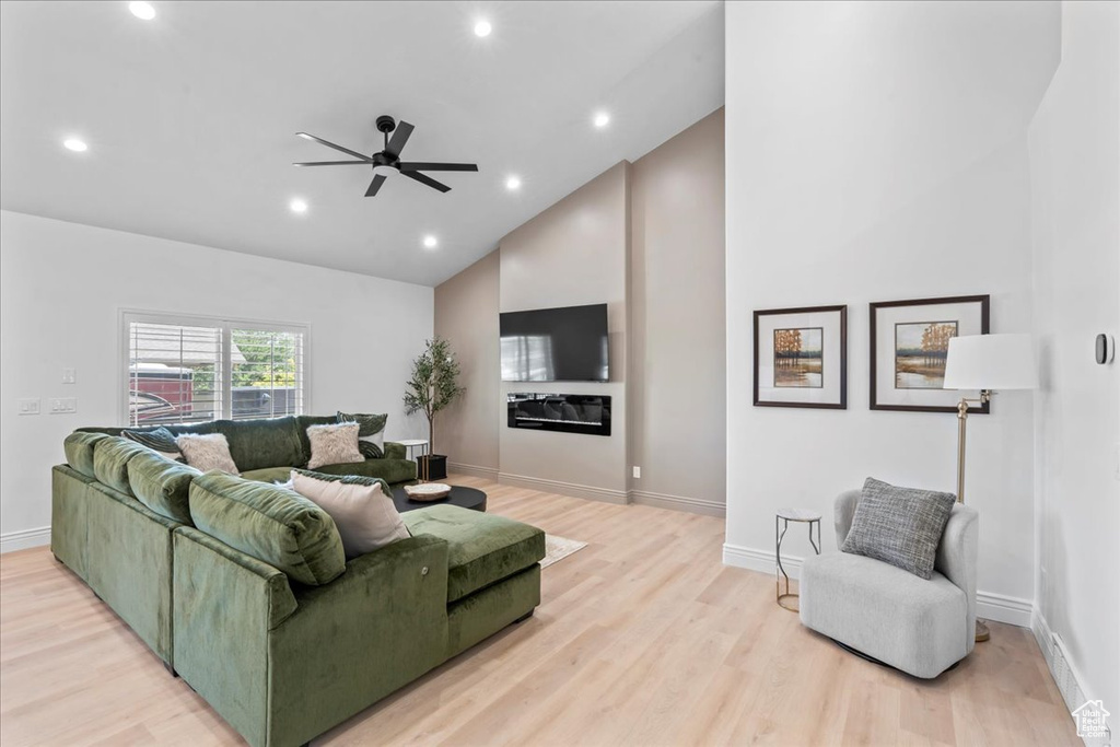Living area with high vaulted ceiling, a ceiling fan, light wood-style flooring, and recessed lighting