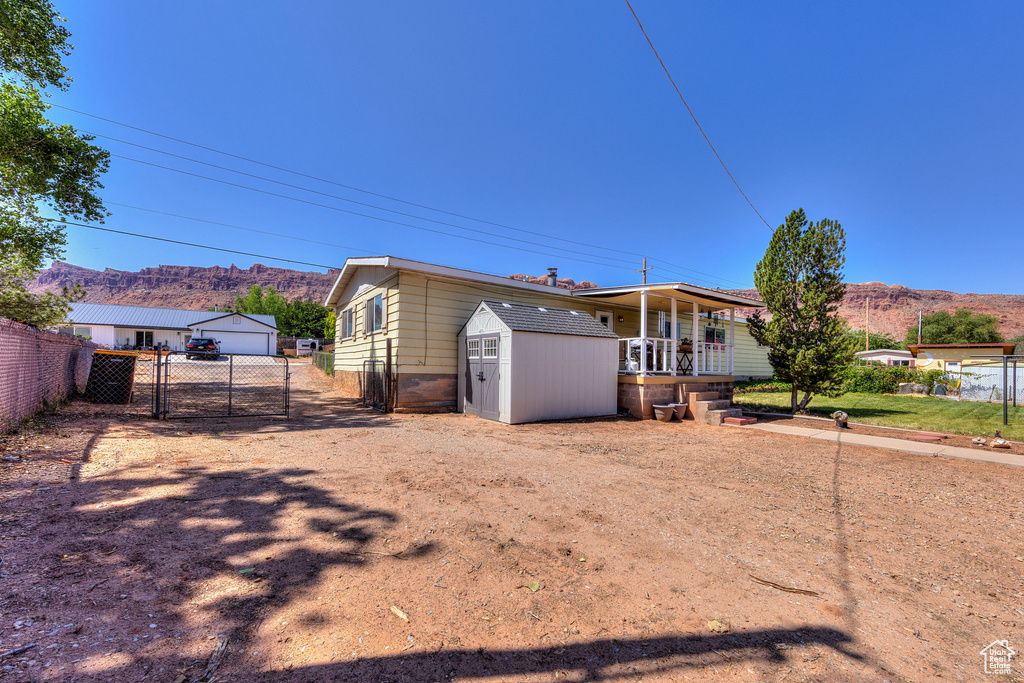 View of front facade with a mountain view, a detached garage, covered porch, and a gate