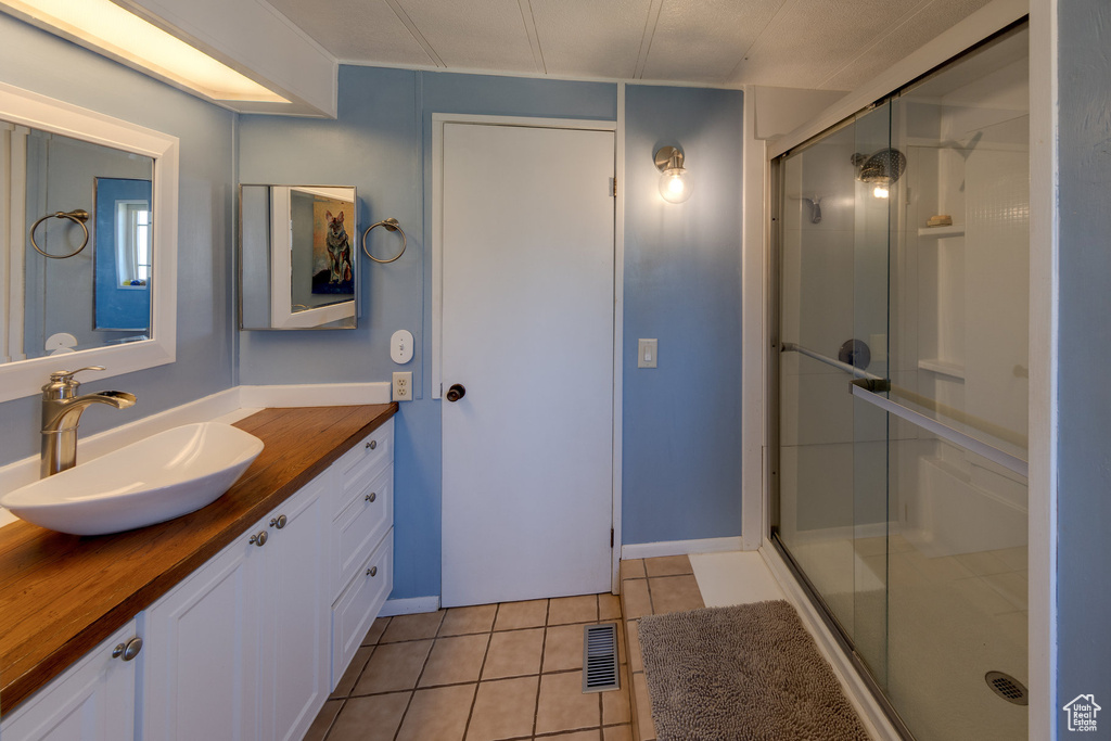 Bathroom with vanity, a shower stall, and tile patterned flooring