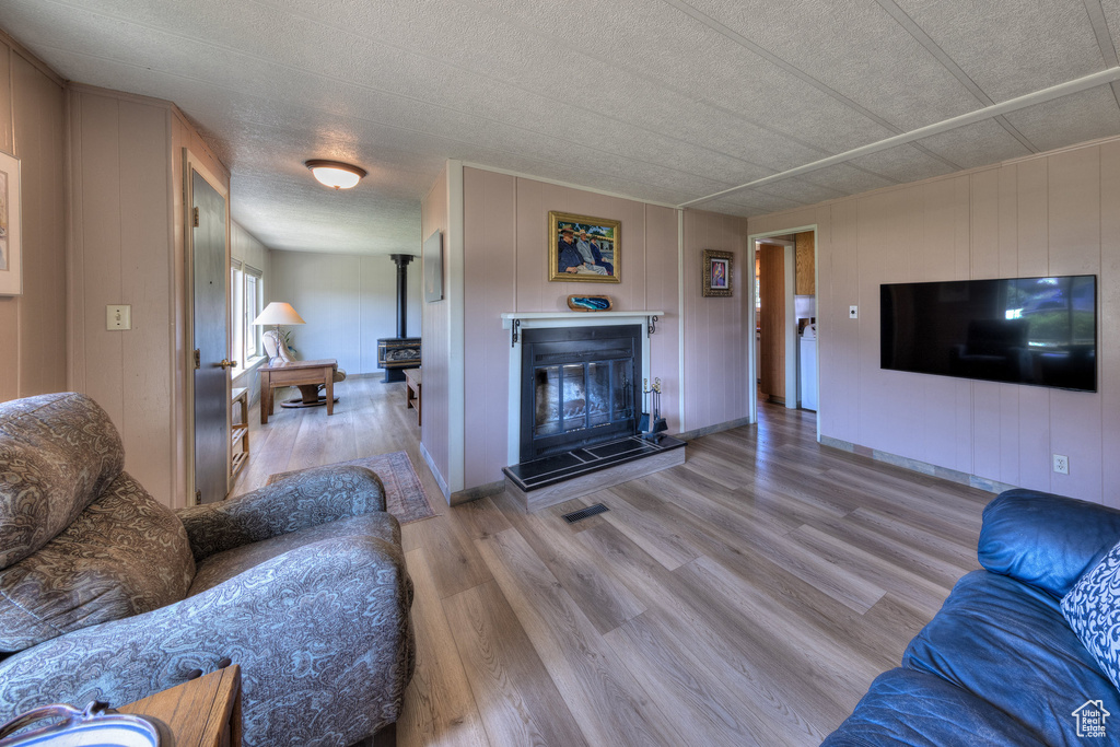 Living room featuring wood finished floors, a decorative wall, a wood stove, and a textured ceiling