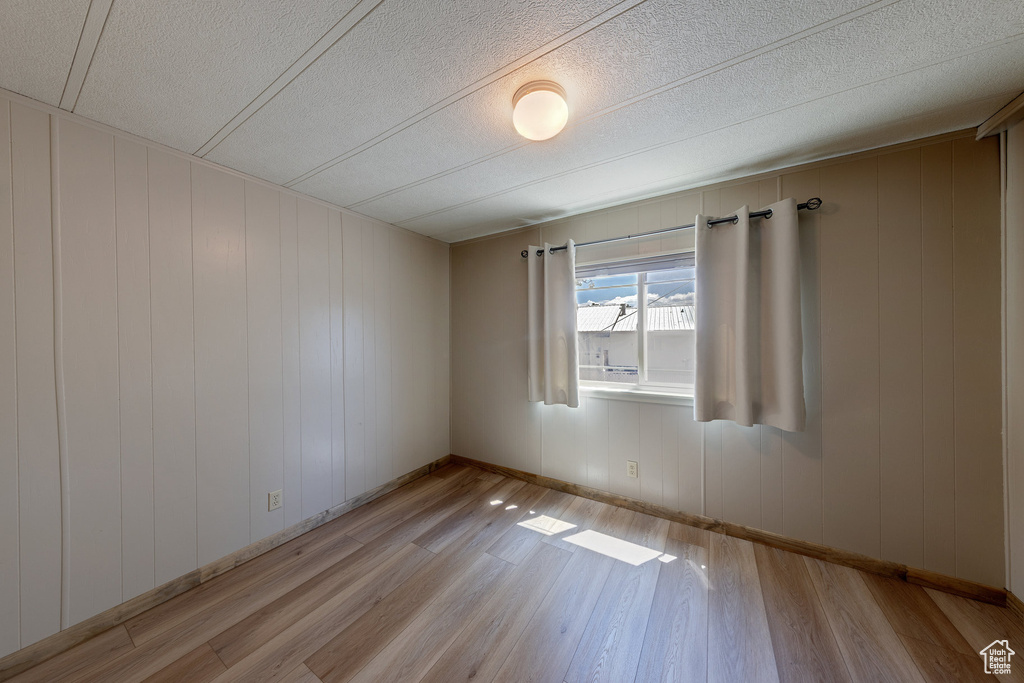 Unfurnished room with light wood-type flooring and a textured ceiling