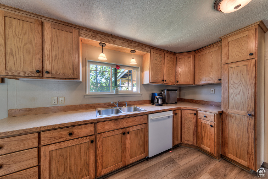Kitchen featuring white dishwasher, light wood finished floors, light countertops, brown cabinets, and a textured ceiling