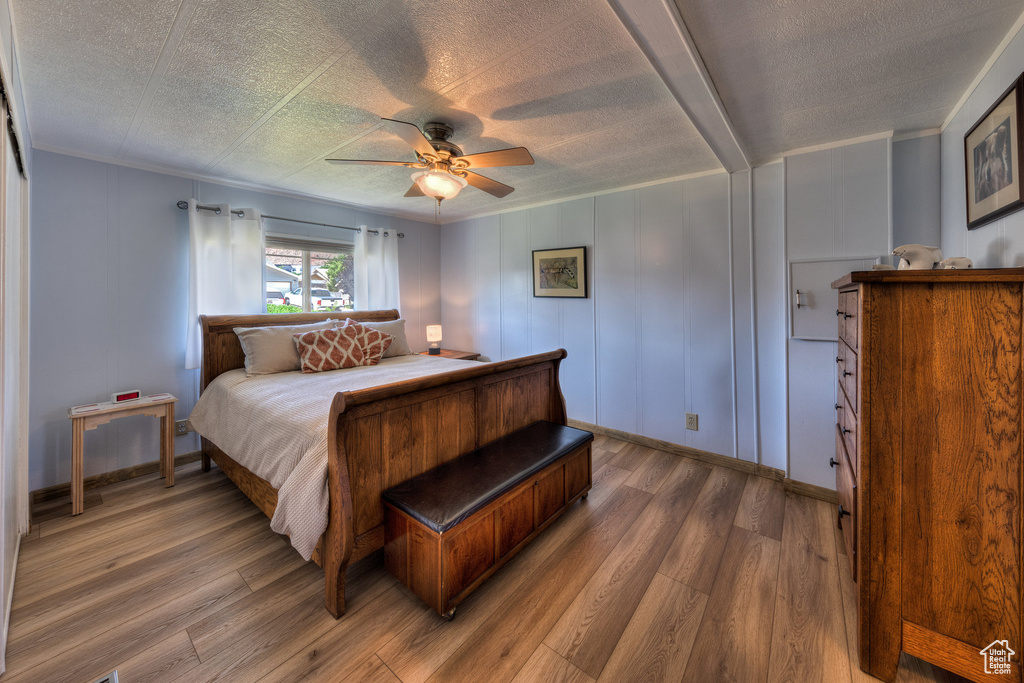 Bedroom with wood finished floors, a ceiling fan, crown molding, and a textured ceiling