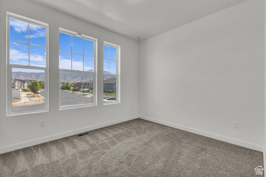 Carpeted spare room featuring baseboards