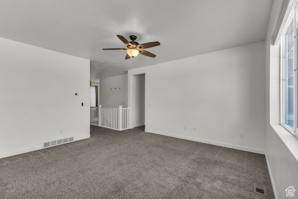 Carpeted spare room featuring a ceiling fan and baseboards