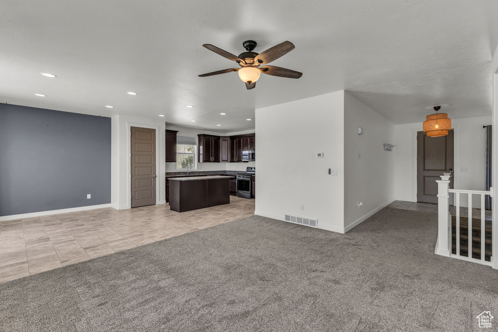 Unfurnished living room featuring a ceiling fan, recessed lighting, and light colored carpet