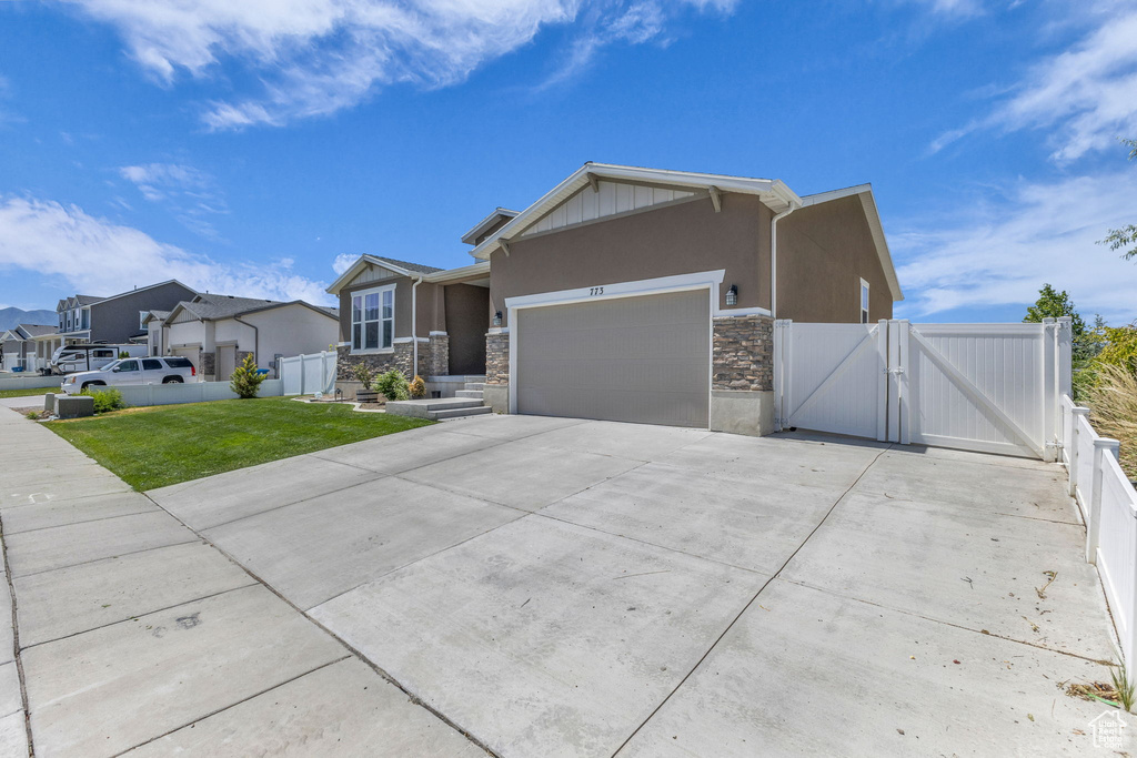 View of front of property featuring a gate, a garage, stone siding, driveway, and stucco siding