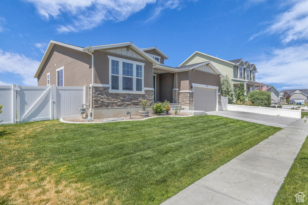 View of front facade featuring stone siding, a gate, concrete driveway, stucco siding, and an attached garage