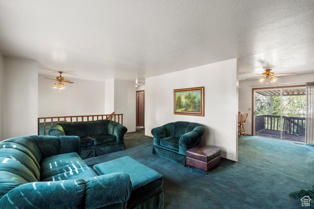Carpeted living area featuring ceiling fan and a textured ceiling