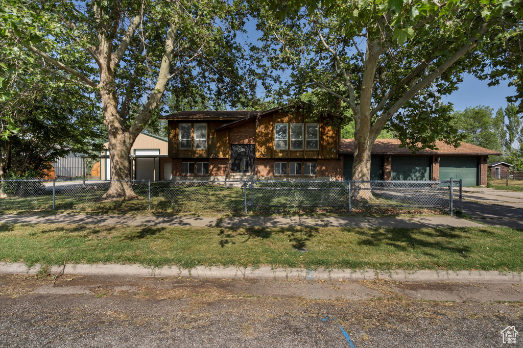 View of front facade featuring brick siding, a fenced front yard, and a garage
