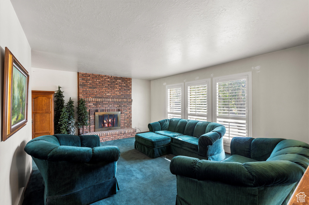Living room with carpet flooring, a fireplace, and a textured ceiling