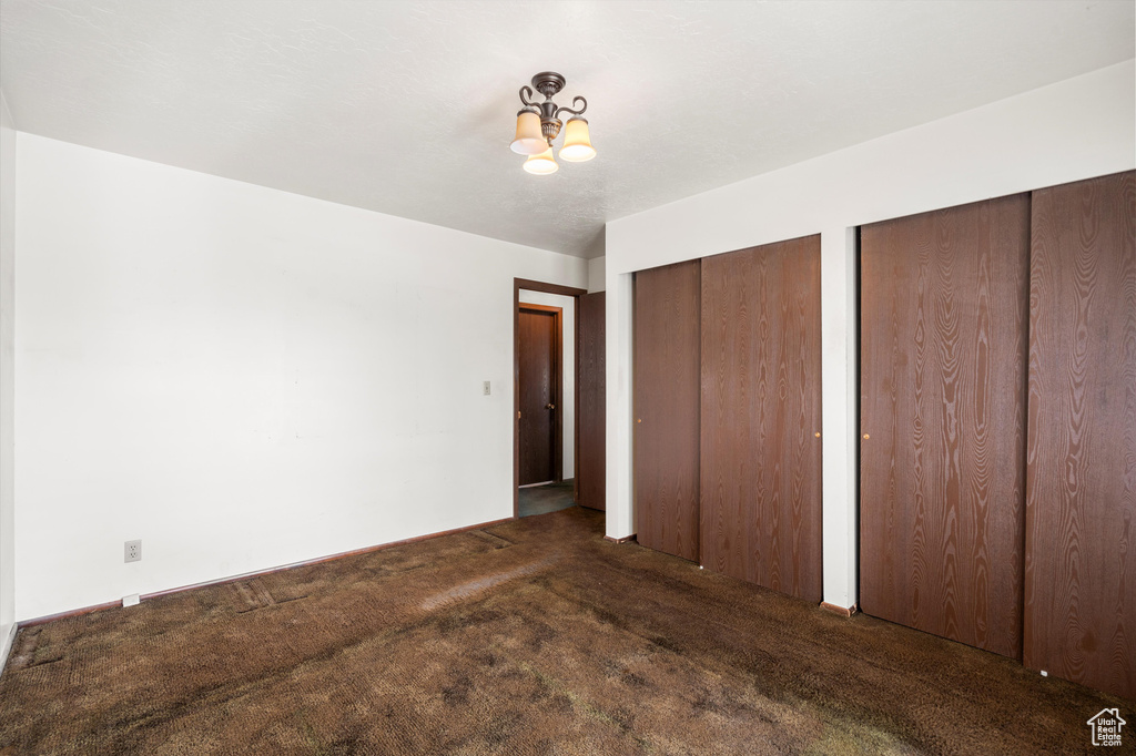 Unfurnished bedroom featuring two closets, a chandelier, and carpet flooring