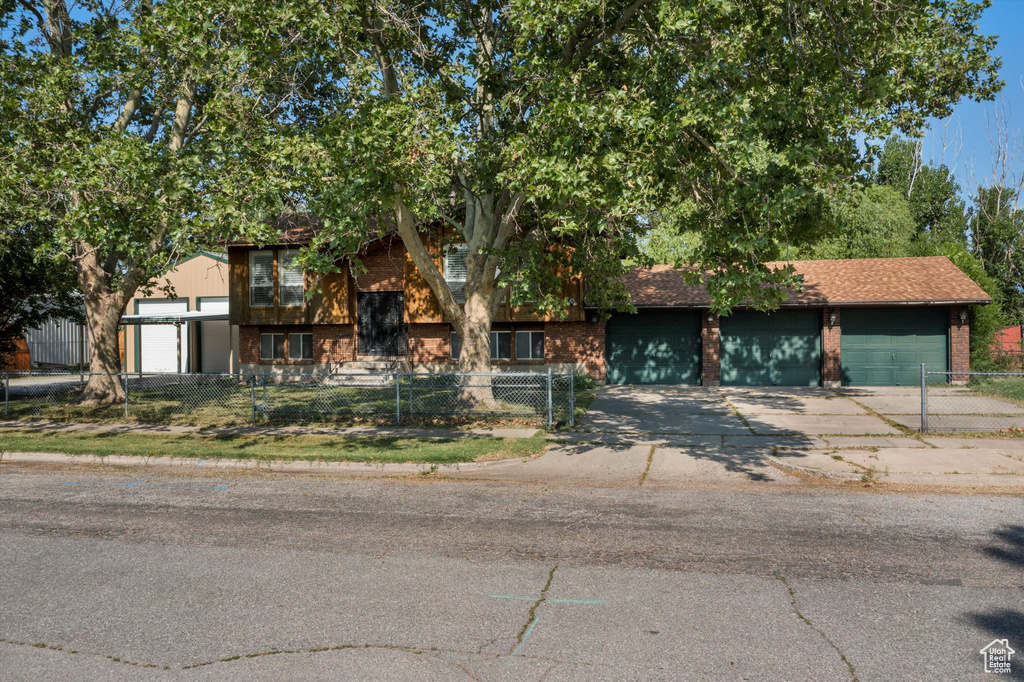 View of front of house featuring a fenced front yard, brick siding, driveway, and a garage