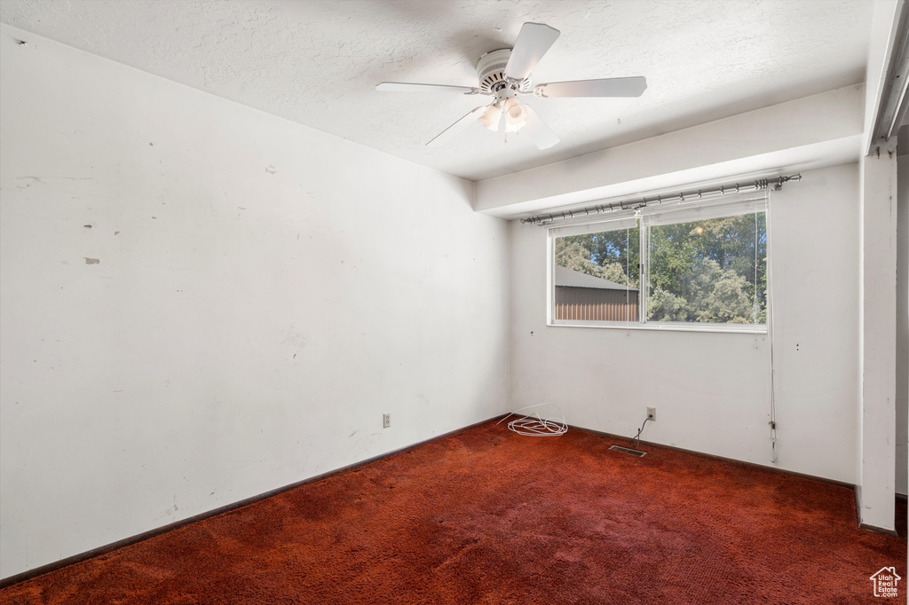Unfurnished room featuring carpet flooring, a textured ceiling, and ceiling fan