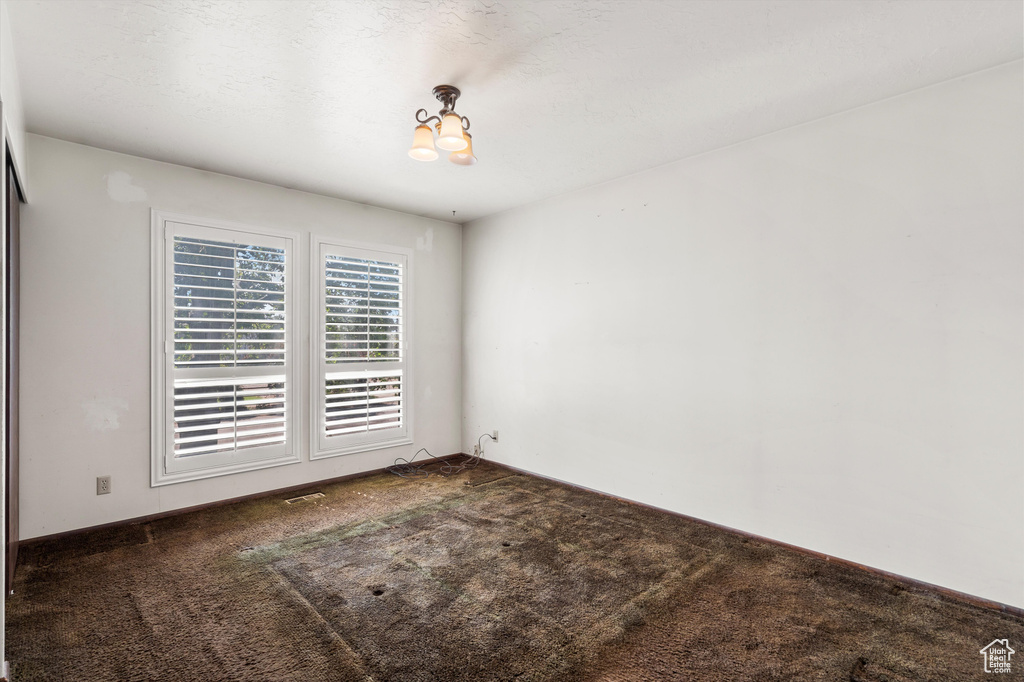 Spare room with carpet floors and a chandelier