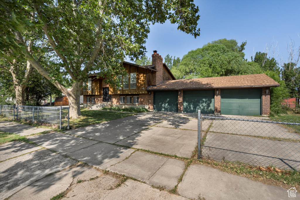 View of front facade with concrete driveway, brick siding, a garage, and a chimney