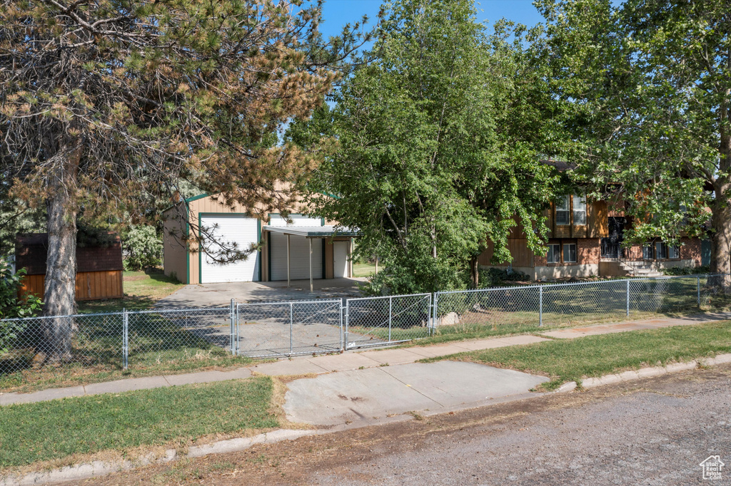 Fenced front yard featuring a gate, a detached garage, and an outbuilding