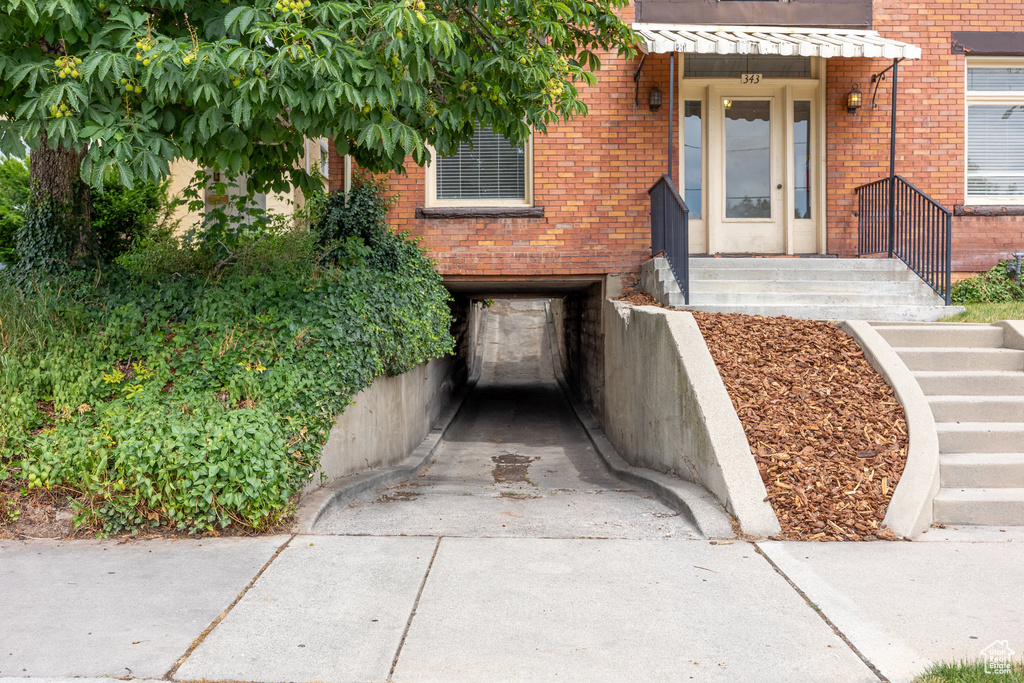 Entrance to property featuring brick siding, driveway, and an attached garage