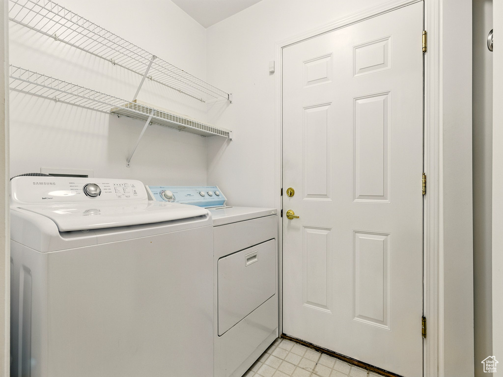 Laundry room with washing machine and clothes dryer and light tile patterned floors