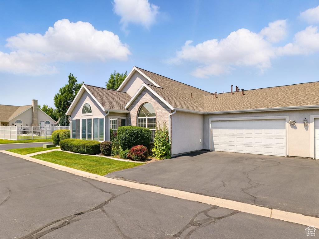 Single story home featuring asphalt driveway, stucco siding, a garage, and a shingled roof