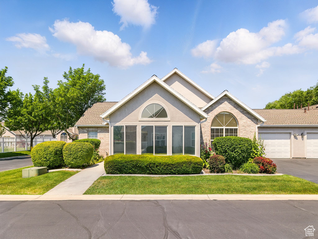 View of front facade with stucco siding, a front lawn, and asphalt driveway