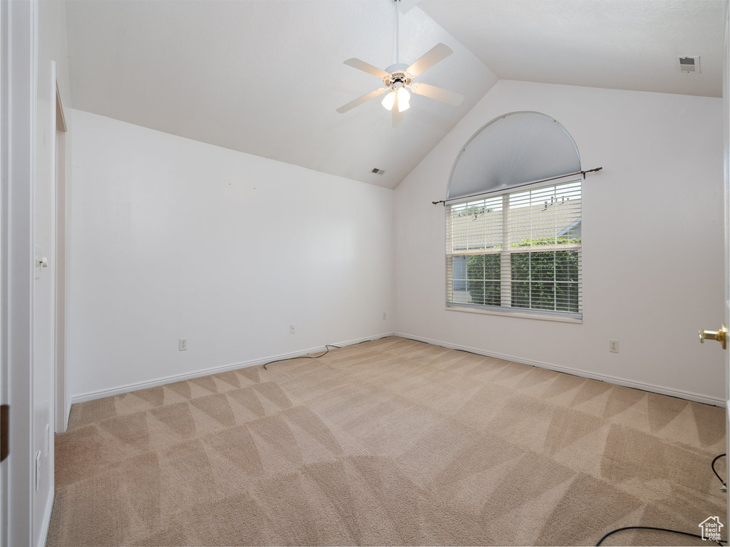 Spare room featuring carpet floors, ceiling fan, and vaulted ceiling