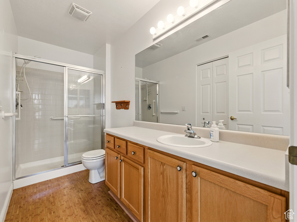 Bathroom with vanity, a stall shower, and wood finished floors
