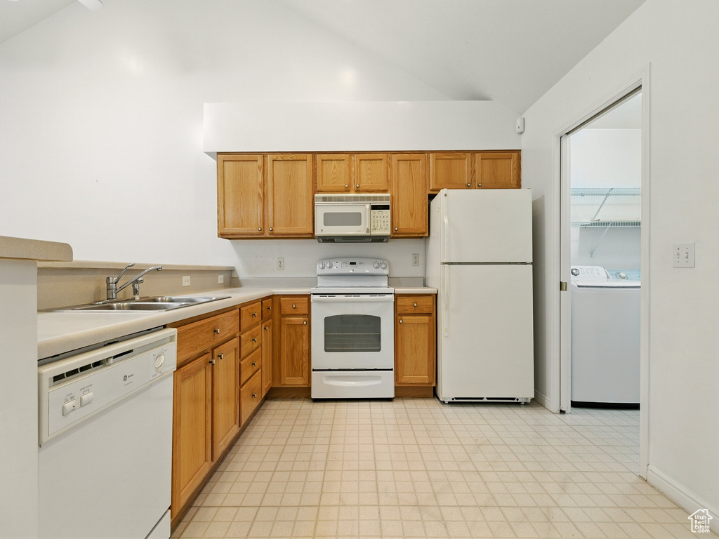 Kitchen featuring white appliances, lofted ceiling, light countertops, and brown cabinets