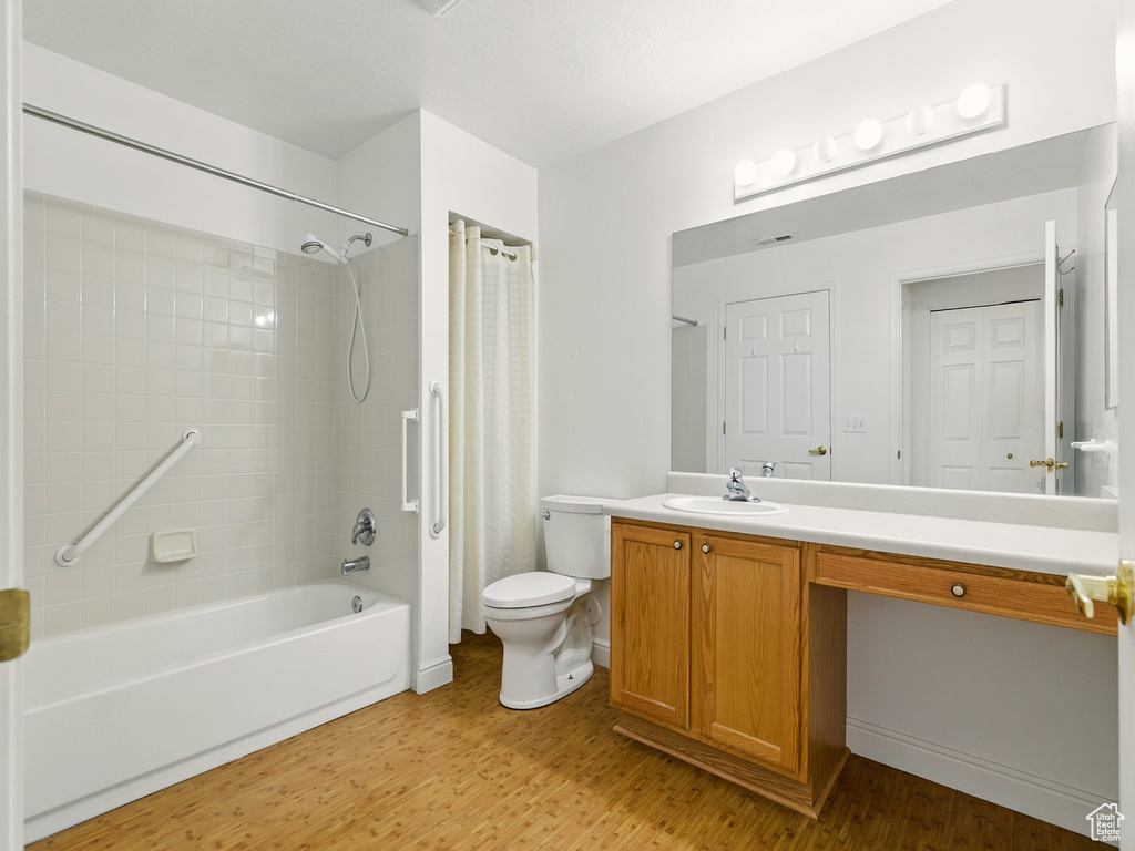 Full bathroom with shower / bath combo, vanity, and wood finished floors